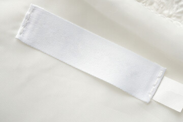Blank white laundry care clothes label on fabric texture background