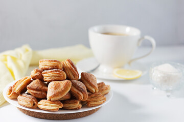 Cottage cheese cookies crow's feet in a plate on a gray background with a cup of tea and textiles.