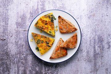 Spanish omelette with potatoes and spinach. Two pieces of bread with tomato. Typical tapas of Barcelona.