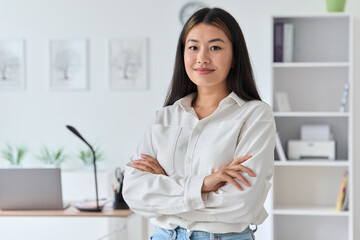 Smiling confident young asian woman standing at home office portrait