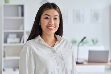 Indoor headshot portrait of young asian woman smiling looking at camera