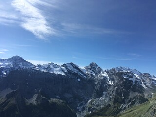 Obraz premium Huge mountains landscape view. Mountains in the summer sunny day in the Switzerland. Nature landscape with mountains, forest and green fields. Travel to Switzerland and mountain landscape. 