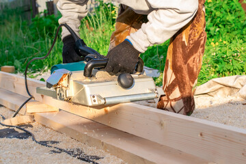 view of a large industrial plane, an electric tool with which a carpenter processes wooden boards while on the street on a country plot