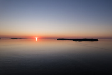 Aerial drone view over the Baltic Sea with small island in distance. Magical sunset at beach.