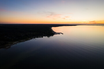 Obraz premium Aerial drone view over small village by the Baltic Sea with small harbor. Magical sunset at seaside port.