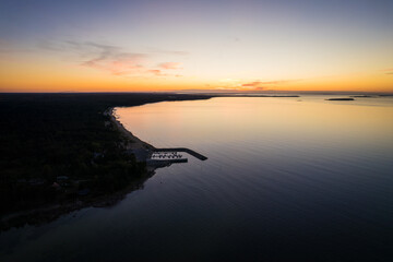 Aerial drone view over small village by the Baltic Sea with small harbor. Magical sunset at seaside port.