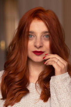 A closeup picture of a red haired and blue eyed woman smiling and looking into the camera 