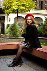 A woman in a red beret sits on a bench