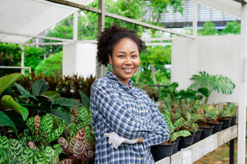 ฺBeautiful african american girl in nursery indoor landscaping in the greenhouse. Happy African...