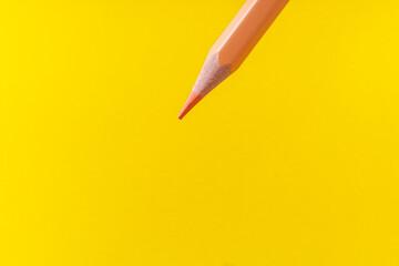 Colored pencil close-up with selective focus on the stylus and a blurred yellow background. Copy space