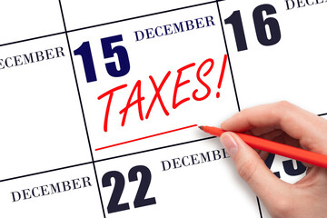 Hand drawing red line and writing the text Taxes on calendar date December 15. Remind date of tax payment