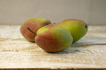 Green yellow pears in brown wooden bowl on rough wooden background, top view.