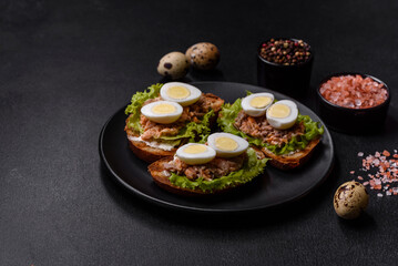 Delicious fresh sandwiches with toast, canned salmon, salad and quail eggs