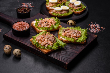Delicious fresh sandwiches with toast, canned salmon, salad and quail eggs