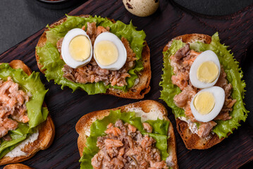 Delicious fresh sandwiches with toast, canned salmon, salad and quail eggs