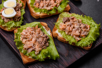 Delicious fresh sandwiches with toast, canned salmon, salad and quail eggs