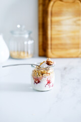 Oatmeal Granola with greek yogurt and nuts strawberry muesli in jars on light background