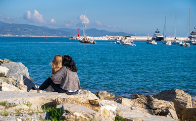 woman with little girl sitting by the sea