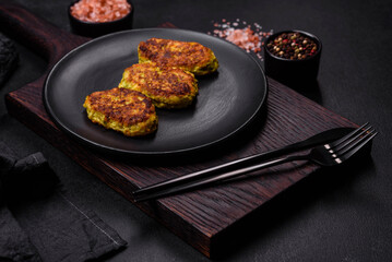 Diet vegetable cutlet from zucchini, carrot, herbs on a black plate
