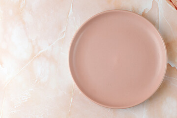 Empty pink blank plate on beige pink marble background. Minimalist mock up for product presentation.
