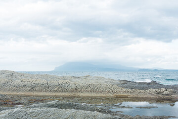 rocky seashore made of columnar granite, hardened lava, resembling scales or cobblestone pavement, coast of Kunashir island