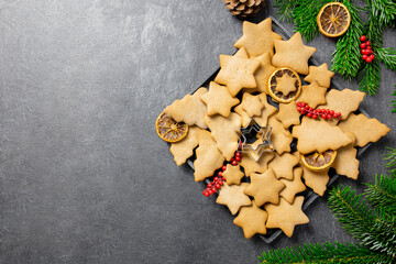 Christmas traditional gingerbread cookies on a plate with decoration, spices and christmas tree branches on dark background. Top view. Copy space.