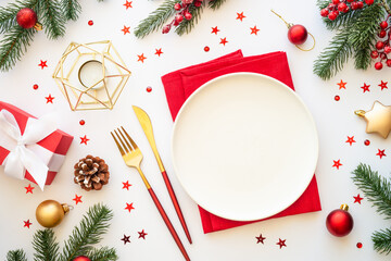 Christmas food, christmas table setting with white plate, golden cutlery and christmas decorations on white background. Top view.
