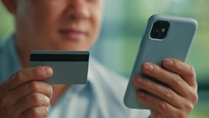 Male customer adult asian man japanese korean buyer businessman paying online in mobile banking app using credit bank card for electronic money transfer safe payments modern tech buying distantly easy - Powered by Adobe