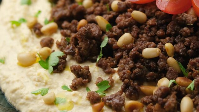 Hummus with spiced ground beef, olive oil, tomatoes and toasted pine nuts. Rotating video