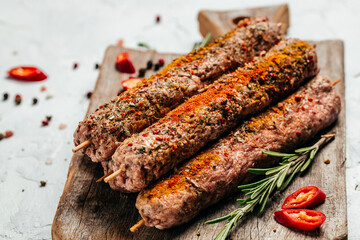 raw Lula kebab on skewers with spices on plate wooden board on a light background. place for text,...
