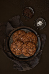 Chocolate brownie cookies with sea salt fleur de sel served on a vintage metal tray. Ingredients on a brown background. Homemade pastry. Top view. Copy space. Low key