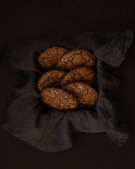 Chocolate brownie cookies with sea salt fleur de sel on a grey linen kitchen towel in a box. Brown background. Homemade pastry. Top view, Low key