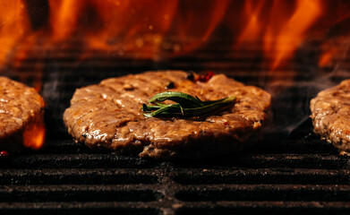 Grilled cutlet burger with flames. raw beef steak on a BBQ grill. banner, menu, recipe place for text, top view