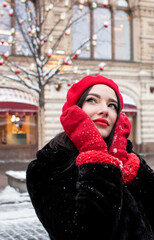 beautiful girl in a red beret and mittens in winter on New Year's street.