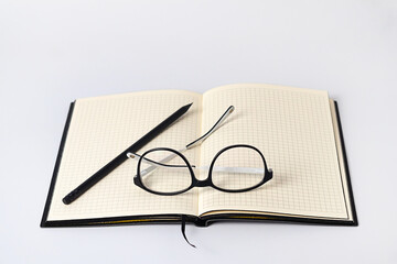 Close up of notebook, pencil and eyeglasses on light background, medical health concept, poor eyesight