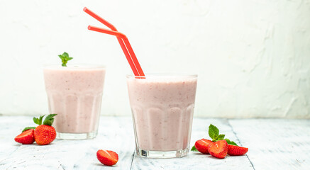 Two glasses of Strawberry smoothie or milkshake with berries and yogurt on white background. Vegetarian healthy drink. place for text