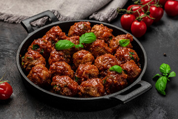 Meat or vegetable meatballs in tomato sauce in frying pan on dark background, top view