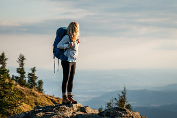 Woman hiking in mountains. Tourist with backpack on mountain peak