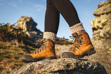 Hiking boot. Trekking in mountains. Female legs walking on rock