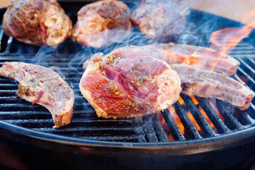Rohe traditionelle Grill Lammhaxen und Sattel gegrillt als close-up auf einem Holzkohlegrill mit Feuer und Rauch