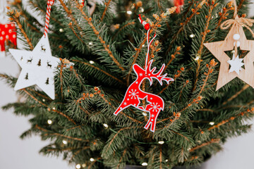 Christmas tree with different wooden decorations. Christmas garland and Christmas lights. White and red colors. Christmas deer, star, snowflake, Bullfinch