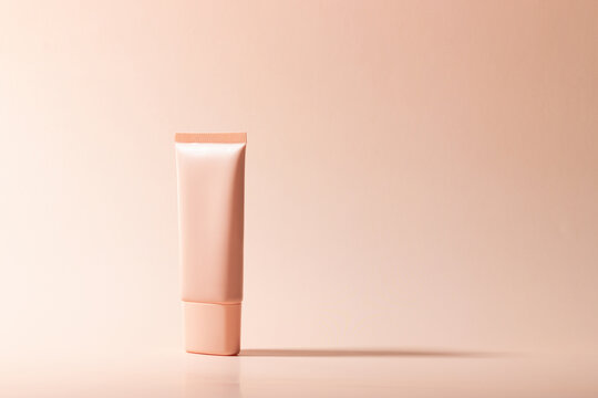 Cosmetic cream or mask in a white tube with hard shadows from the leaves on a white background. Natural organic care for face and body skin. View from above.
