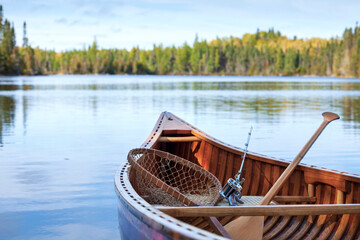 Selective focus view of wooden canoe with vintage fishing rod and net on a Boundary Waters lake