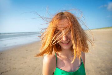 fröhliches Mädchen mit zerzausten Haaren am Strand