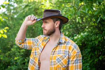Obraz premium caucasian man in cowboy hat. sexy cowboy in checkered shirt. western cowboy wearing hat