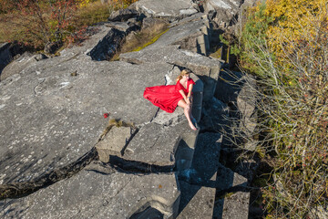 aerial view on girl in red dress lying on rock or concrete ruined structure