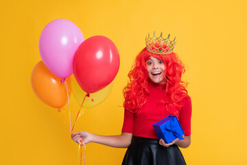 happy child in crown with present and party balloon on yellow background. wow