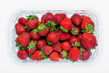 Top view of a package with ripe bright red strawberries on a white background