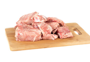 Wooden cutting board with raw pork stew on a white background.