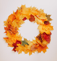 Naklejka na ściany i meble A wreath of autumn fallen leaves of different sizes and colors on a light background, copy space, autumn concept